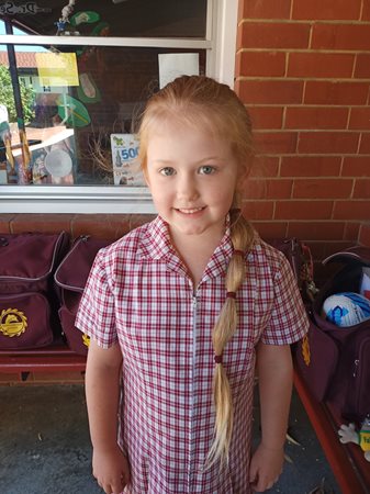 Imogen stands proudly in her school uniform showing off her long locks.