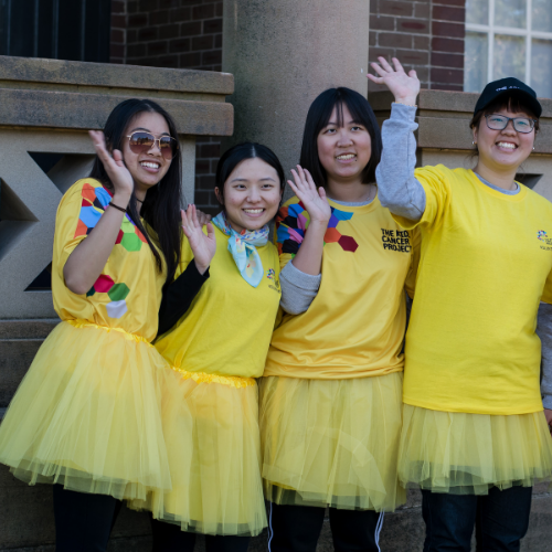 Four young people proudly smile and wave while dressed up in TKCP 