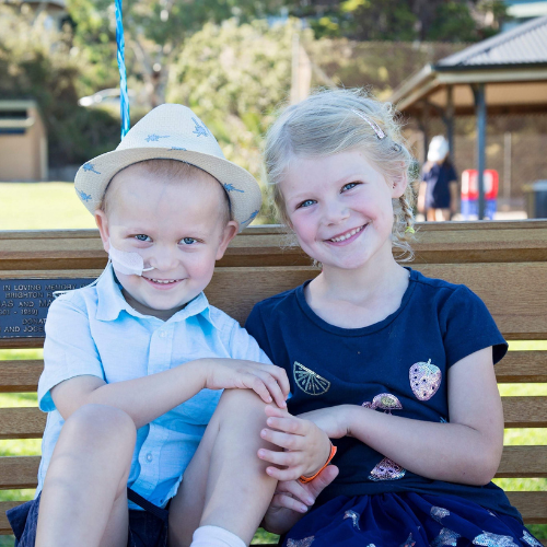 Ollie sitting on a bench with his big sister