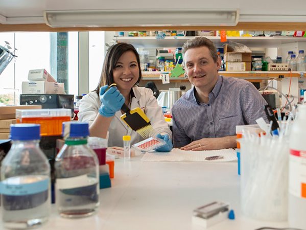 Professor Nick Gottardo sits next to Dr. Raelene Endersby in a lab.
