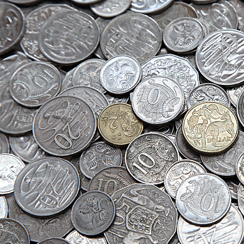 A table covered in loose change; coins from 5 cents up to 2 dollars are scattered across the surface.