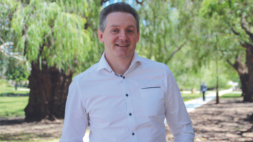 Professor Nick Gottardo smiles while standing in a scenic park.