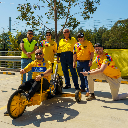 A team of people wearing TKCP tee-shirts gather around a go-kart in preparation for a race.