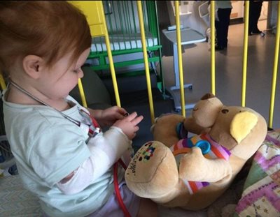 Young girl in hospital with cancer charity bear
