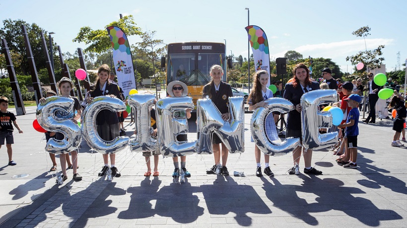 Childhood cancer survivors holding silver balloon letters that spell SCIENCE