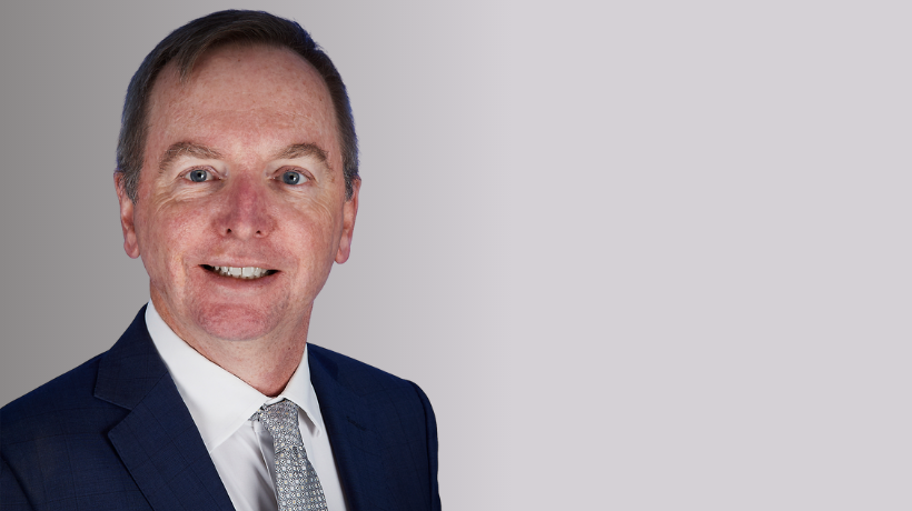 Associate Professor Geoff McCowage smiles at the camera against a neutral backdrop.