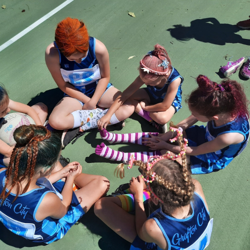 Students sit in a circle wearing bright and unusual socks and hairstyles.