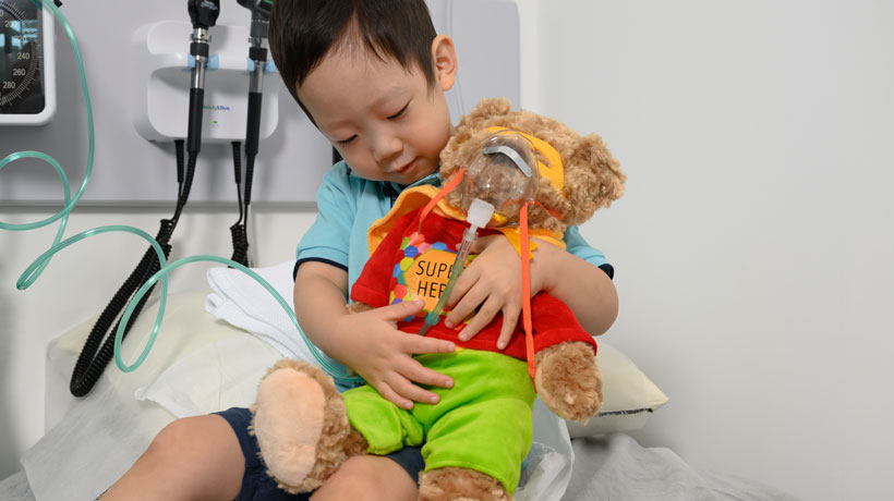 Child in hospital hugging charity super bear improving outcomes
