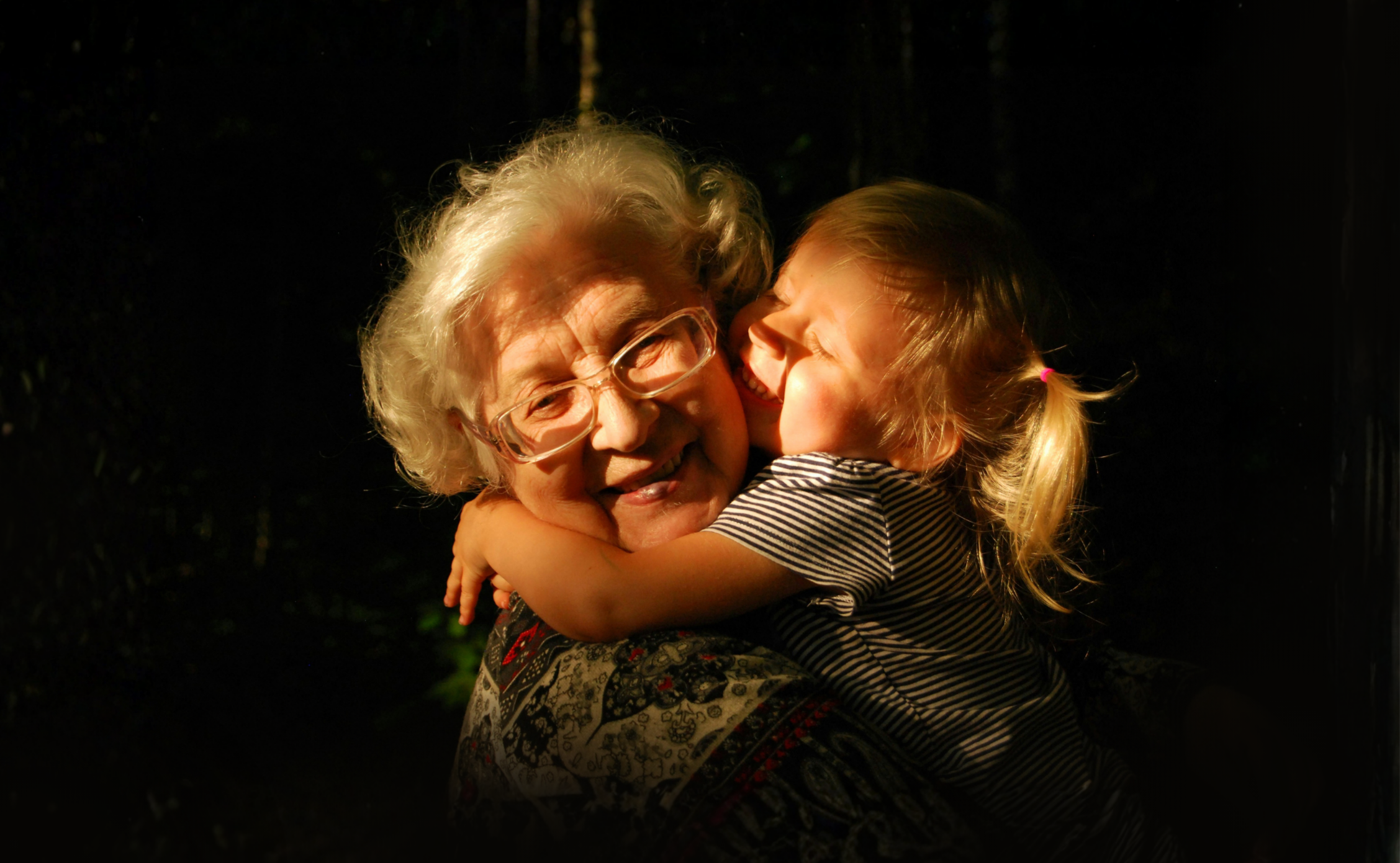 Older woman being hugged by a young child and smiling