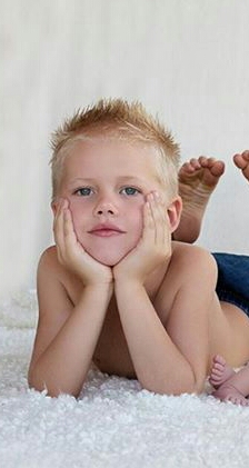 Zach poses for a family portrait on a fluffy white rug.