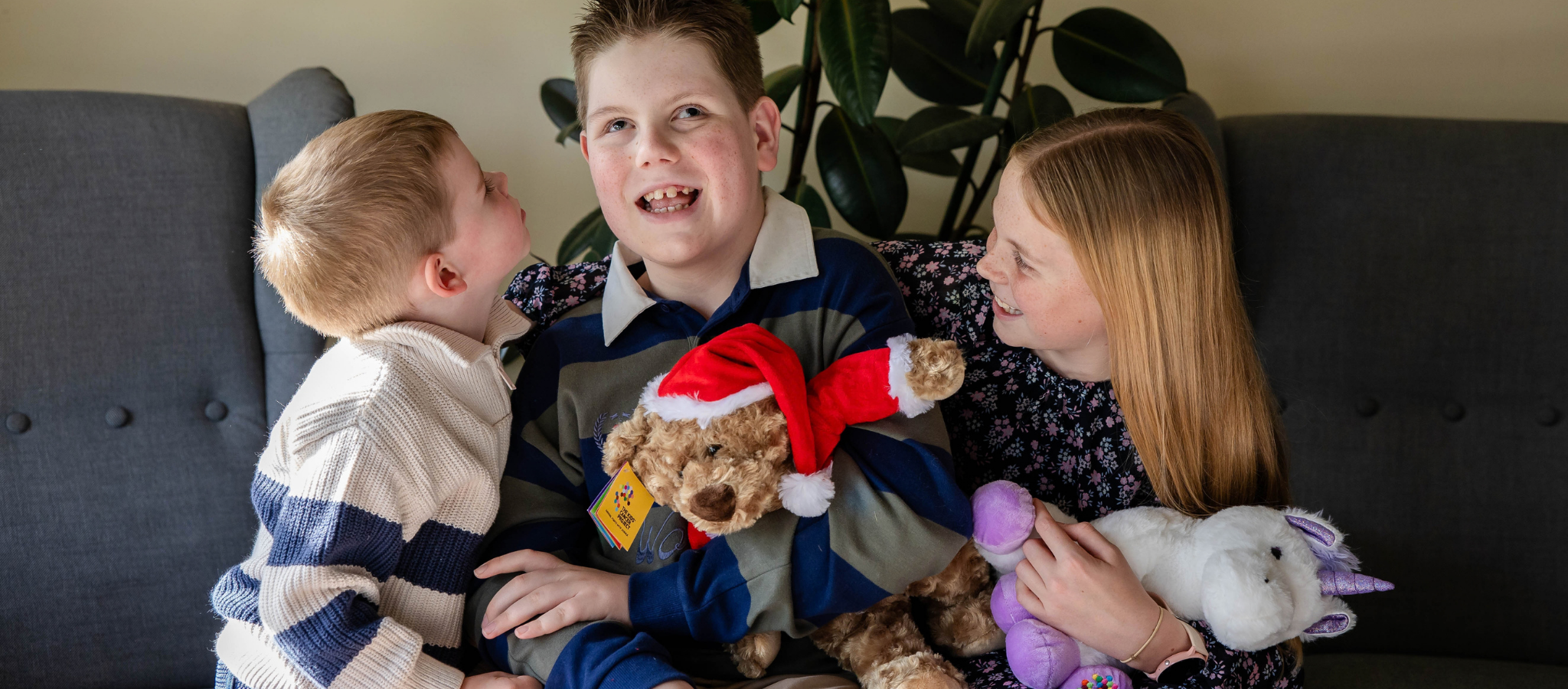 Three children with teddy bears, smiling at the camera.
